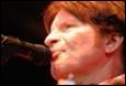 A person with red hair singing into a microphone

Description automatically generated