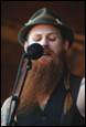 A person with a beard singing into a microphone

Description automatically generated
