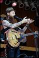 A person with a beard singing into a microphone

Description automatically generated