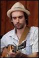 A person in a hat playing a guitar

Description automatically generated