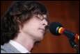 A person with glasses and a microphone

Description automatically generated