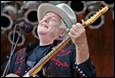A person in a cowboy hat holding a guitar

Description automatically generated