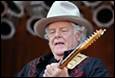 A person in a hat playing a guitar

Description automatically generated