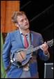 A person in a suit playing a mandolin

Description automatically generated