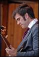 A person in a suit holding a guitar

Description automatically generated