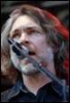A person with long hair and a microphone in his mouth

Description automatically generated