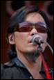 A person wearing sunglasses and singing into a microphone

Description automatically generated