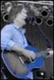 A person playing guitar and singing into a microphone

Description automatically generated