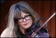 A person with glasses holding a violin

Description automatically generated