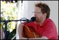 A person with a beard playing a guitar

Description automatically generated