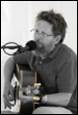 A person with a beard and a guitar

Description automatically generated