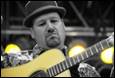 A person in a hat playing a guitar

Description automatically generated