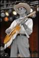 A person in cowboy hat playing a guitar

Description automatically generated