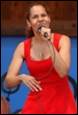 A person in a red dress holding a microphone

Description automatically generated