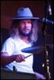 A person with long hair playing drums

Description automatically generated