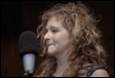 A person with curly hair and a microphone

Description automatically generated