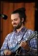 A person with a beard and a guitar

Description automatically generated