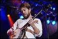 A person playing a banjo on stage

Description automatically generated