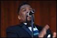 A person in a suit singing into a microphone

Description automatically generated