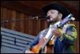 A person with a hat and guitar

Description automatically generated