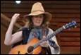 A person wearing a hat playing a guitar

Description automatically generated