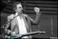 A person holding a guitar and raising his fist

Description automatically generated
