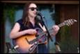 A person playing a guitar and singing into a microphone

Description automatically generated