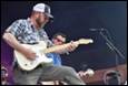 A person playing guitar on stage

Description automatically generated