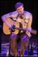 A person playing guitar and singing

Description automatically generated